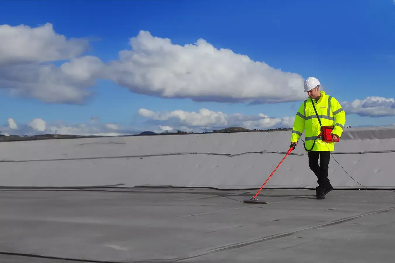 Contractor performing electronic leak detection (ELD) on a flat roof